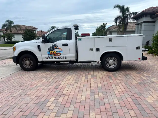 Side profile of the Ox Air & Heat Ford F-250 service truck showing the utility body tool compartments and the Florida contractor license number on the fender.